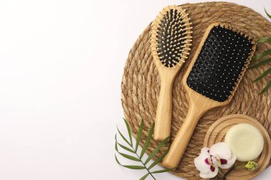 Tahta saç fırçaları, sağlam şampuan, orkide çiçekleri ve beyaz arka planda yapraklar. Metin için boşluk