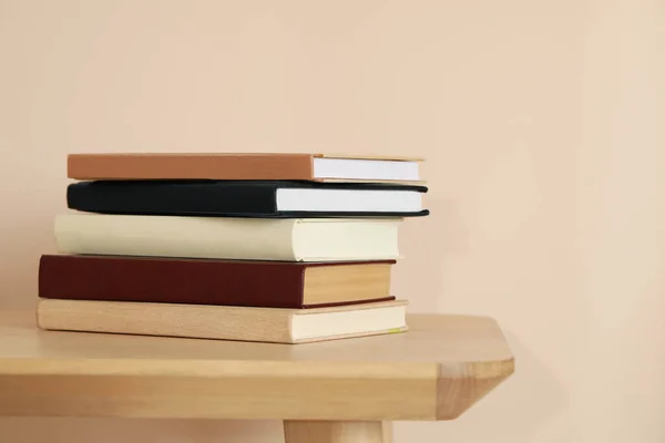 Viele Hardcover Bücher Auf Holztisch Nahe Beiger Wand — Stockfoto
