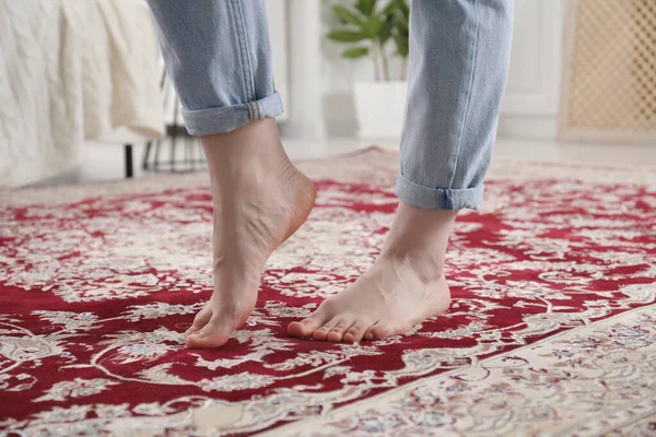 Woman standing on carpet with pattern at home, closeup