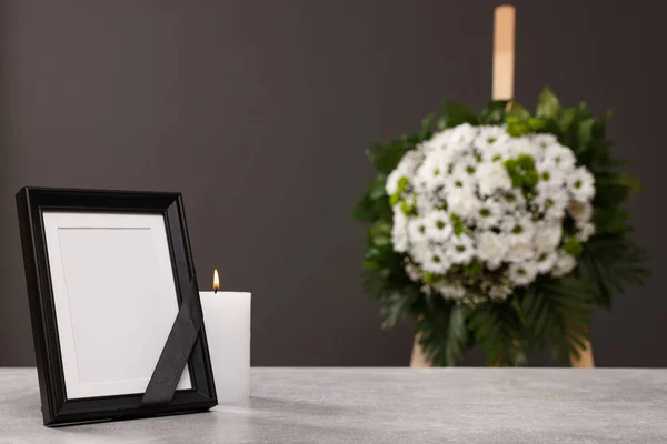黒いリボンで写真フレーム テーブルの上にろうそくを燃やし 屋内で灰色の壁の近くの花の花輪 テキストのためのスペース 葬儀の属性 — ストック写真