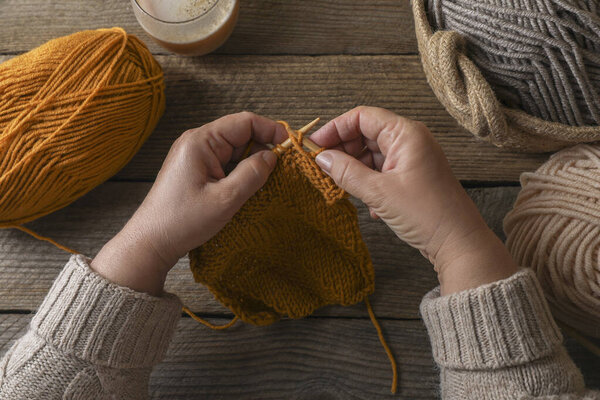 Woman knitting at wooden table, top view. Creative hobby
