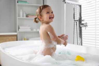 Evde köpüklü banyo yapan tatlı küçük kız.