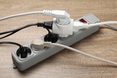 Tahta zeminde uzatma kablosu olan güç şeridi. Elektrikçi ekipmanı.