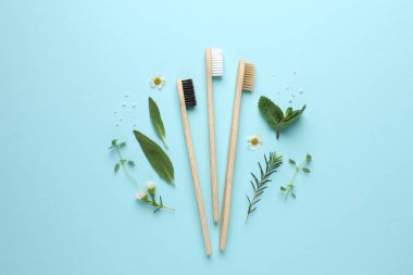Bambu diş fırçaları, güzel papatya çiçekleri, turkuaz arka planda deniz tuzu ve otlar.