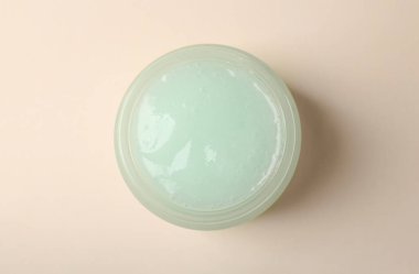 Bej arka planda bir kavanoz aloe jeli, üst görünüm