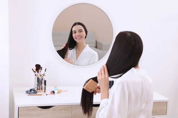 Mulher Bonita Escovando Cabelo Enquanto Olha Espelho Mesa Vestir Dentro — Fotografia de Stock