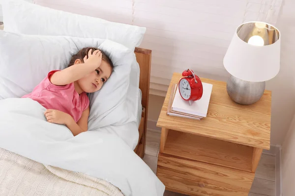 Kleines Mädchen Liegt Bett Und Schaut Auf Wecker Auf Nachttisch — Stockfoto