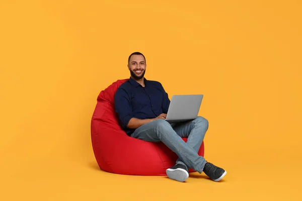 Jovem Sorrindo Trabalhando Com Laptop Cadeira Saco Feijão Contra Fundo — Fotografia de Stock