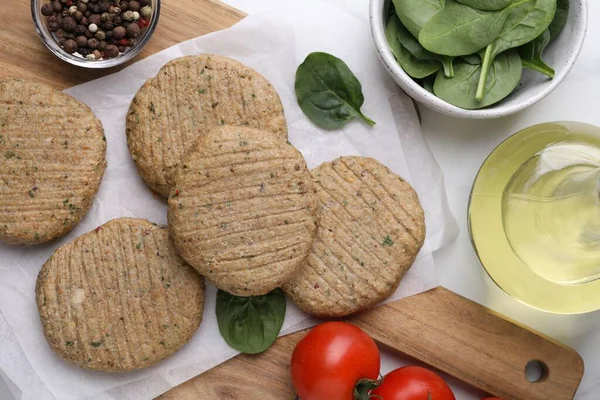 stock image Raw vegan cutlets and different products on white table, flat lay