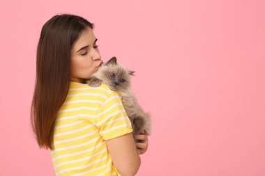 Güzel kedisini pembe arka planda öpen bir kadın, mesaj için boşluk.