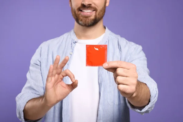 Чоловік Презервативом Показує Нормальний Жест Фіолетовому Тлі Крупним Планом Безпечний — стокове фото