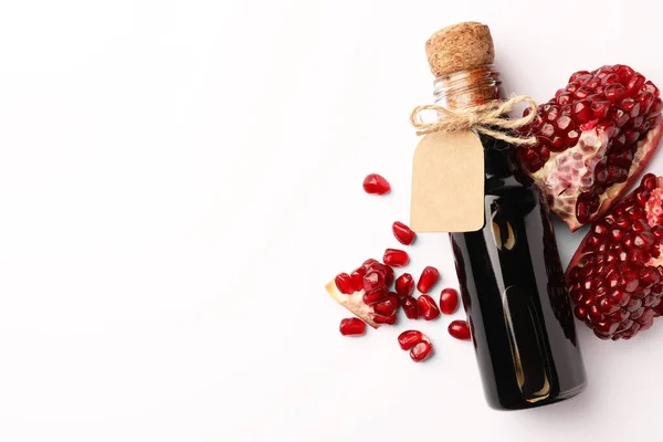 Bottle of pomegranate sauce and fresh ripe fruit on white background, top view. Space for text