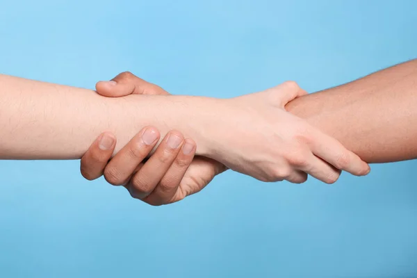 International Relationships People Holding Hands Light Blue Background Closeup — Stock Photo, Image