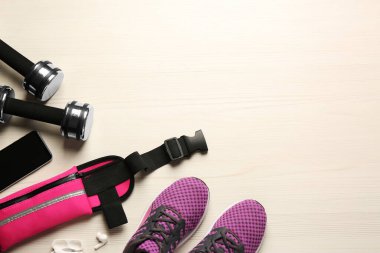 Beyaz ahşap masa üzerinde pembe bel çantalı düz kompozisyon, metin için boşluk