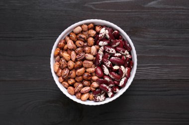 Tahta masadaki kasede farklı türde kuru fasulye var.