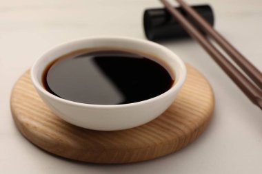 Soya soslu kase ve yemek çubukları beyaz masada, yakın plan.