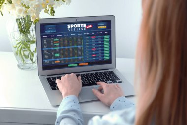 Woman betting on sports using laptop at table, closeup. Bookmaker website on screen clipart