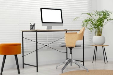Rahat koltuğu, masası, bilgisayarı ve bitkisi olan şık bir ofis.