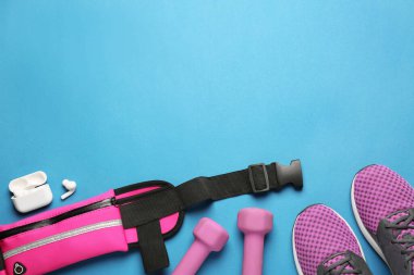 Açık mavi zemin üzerinde şık pembe bel çantalı düz konum, metin için boşluk