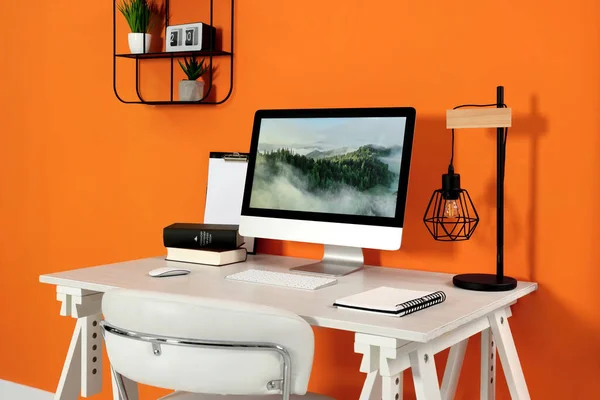 Современный Компьютер Книги Лампа Ноутбук Деревянном Столе Возле Оранжевой Стены — стоковое фото
