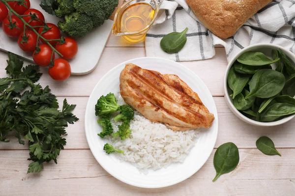 Stock image Grilled chicken breast and rice served with vegetables on wooden table, flat lay