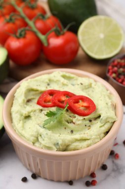 Bir kase lezzetli guacamole ve malzemeler beyaz masada, yakın plan.