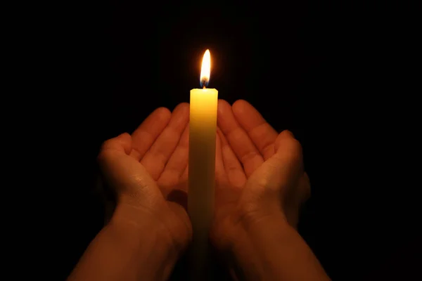 在黑色背景上手握燃烧的蜡烛的女人 — 图库照片