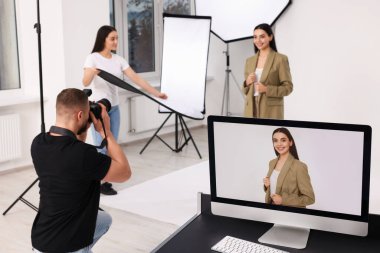 Modern fotoğraf stüdyosunda güzel bir modelle çalışan profesyonel fotoğrafçı ve asistan.