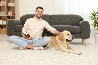 Adam yerde kitap okuyor. Evindeki şirin Labrador Retriever 'ının yanında.