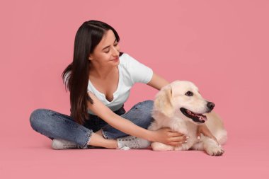 Pembe arka planda şirin Labrador Retriever köpeği olan mutlu bir kadın. Sevimli hayvan.