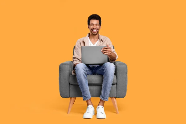 Homem Feliz Com Laptop Sentado Poltrona Fundo Laranja — Fotografia de Stock