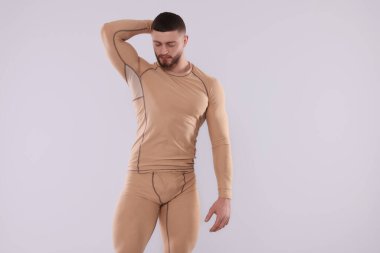 Man in warm thermal underwear on light background. Space for text