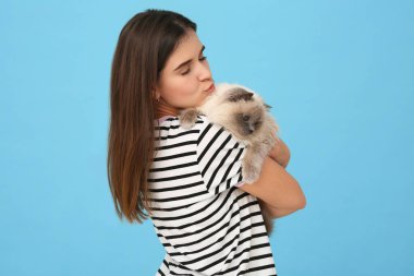 Açık mavi arka planda sevimli kedisini öpen bir kadın, mesaj için boşluk