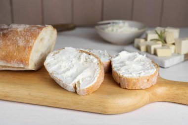 Beyaz ahşap masada tofu krem peynirli baget dilimleri.