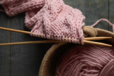 Yumuşak pembe yün iplik, ahşap masa üzerinde örgü ve iğneler, üst manzara