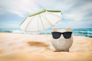 Tatil birikimleri. Kumsalda deniz kenarında güneş gözlüğü ve şemsiyeli bir kumsal.