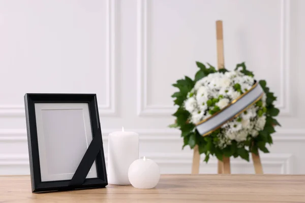 黒いリボンで写真フレーム テーブルの上にろうそくを燃焼し 白い壁の近くの花の花輪を屋内で テキストのためのスペース 葬儀の属性 — ストック写真