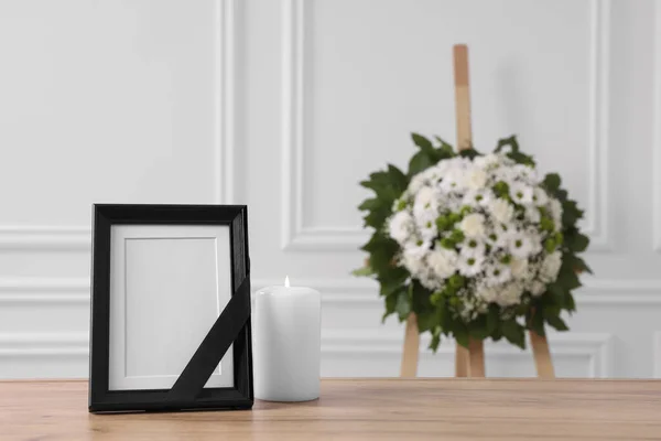 黒いリボンで写真フレーム テーブルの上にろうそくを燃焼し 白い壁の近くの花の花輪を屋内で テキストのためのスペース 葬儀の属性 — ストック写真