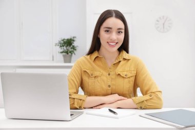 Ofiste dizüstü bilgisayarla çalışan genç bir kadın stajyer.