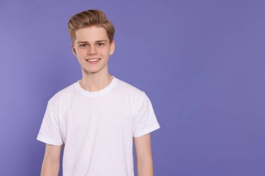 Portrait of teenage boy on purple background. Space for text