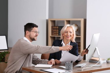 Ofisteki ahşap masada iş meselelerini tartışan patron ve çalışan.