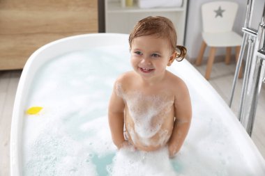 Evde köpüklü banyo yapan tatlı küçük kız.