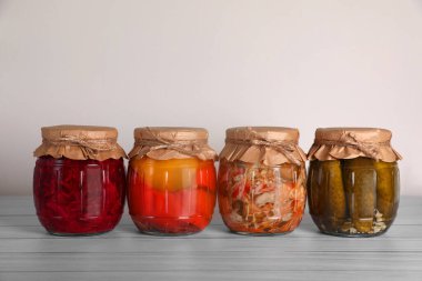Farklı korunmuş sebzelerle dolu kavanozlar ahşap masada.