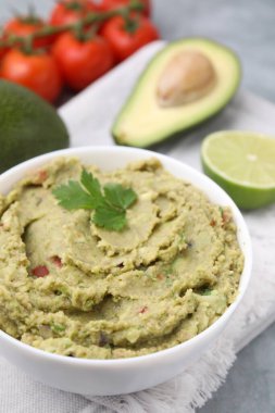Bir kase lezzetli guacamole ve içindekiler gri masada, yakın plan.