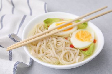 Bir kase lezzetli pirinç şehriye çorbası, kereviz ve yumurta açık gri masada, yakın plan.