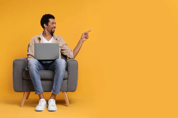Homem Feliz Com Laptop Sentado Poltrona Fundo Laranja Espaço Para — Fotografia de Stock