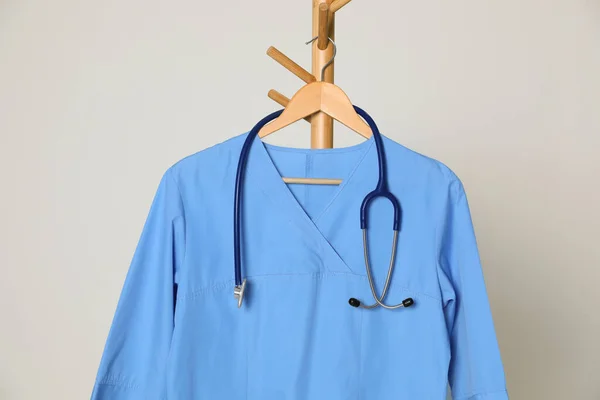 Medicinsk Uniform Och Stetoskop Hängande Rack Mot Ljusgrå Bakgrund — Stockfoto