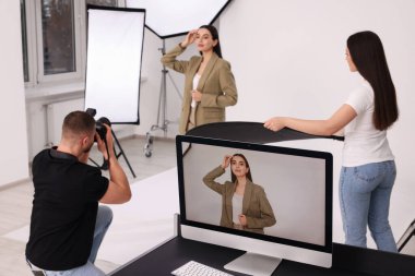 Modern fotoğraf stüdyosunda güzel bir modelle çalışan profesyonel fotoğrafçı ve asistan.