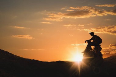 Gün batımında dağların zirvesinde sırt çantalı bir adamın silueti. Metin için boşluk