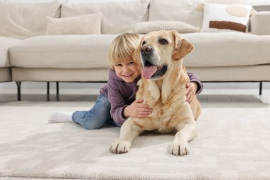 Evinde yerde Golden Retriever 'ı olan sevimli küçük bir çocuk. Sevimli hayvan.